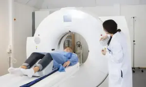 Pacjentka na stole tomografu, lekarz przygotowuje badanie. Może to być związane z dolegliwościami po podaniu kontrastu.