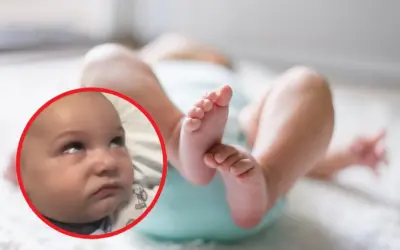 Dziecko z wyrazem twarzy sugerującym niepokój. W tle jego nóżki. Obraz może ilustrować padaczka objawy u niemowląt.