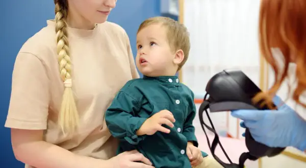 Matka z synkiem u lekarza. Dziecko patrzy z zaciekawieniem na sprzęt medyczny, a rodzicielka z troską. Czy epilepsja jest uleczalna?