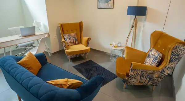 Wnętrze gabinetu psychologicznego z kanapą, fotelami i biurkiem.